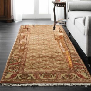 Tan and rust traditional rug with intricate borders runs between a gray couch and wood cabinet.