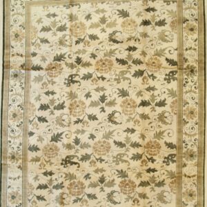 Cream and muted green floral area rug with a wide border displayed on light wood floorboards.