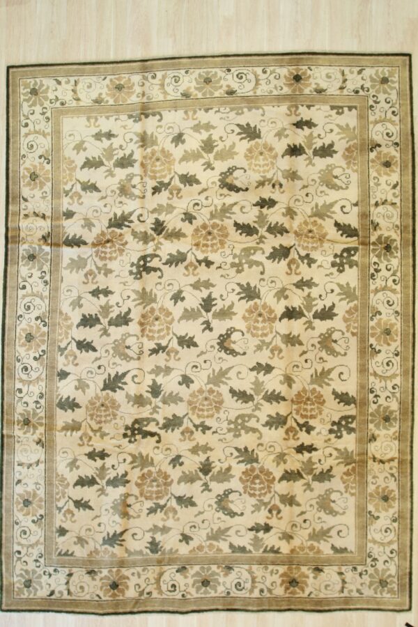 Cream and muted green floral area rug with a wide border displayed on light wood floorboards.