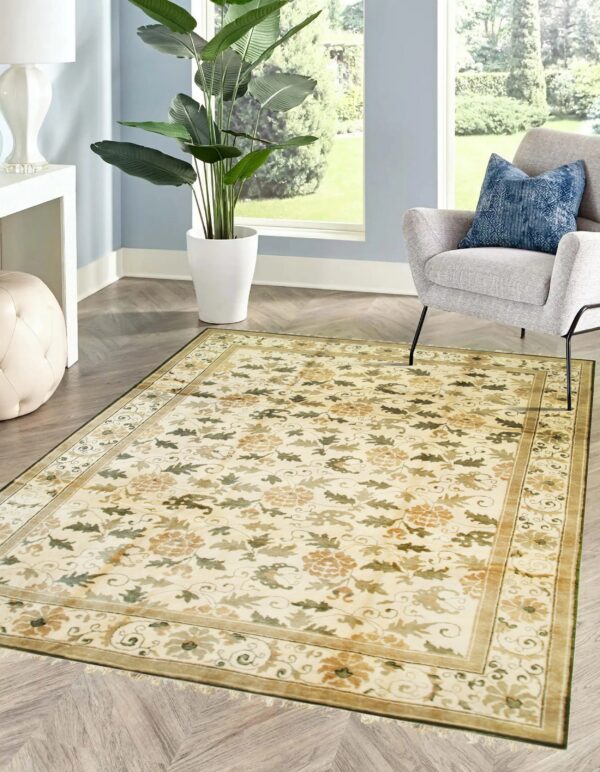 Traditional cream floral rug in a room with light blue walls and a gray armchair.