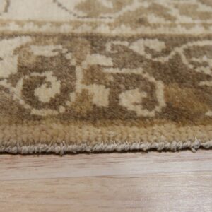 Closeup of the brown and cream patterned rug border showing high pile texture on light wood flooring.