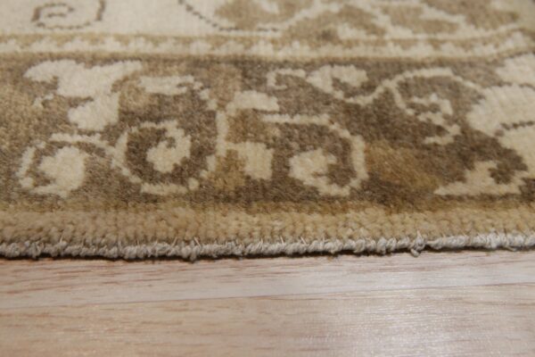 Closeup of the brown and cream patterned rug border showing high pile texture on light wood flooring.