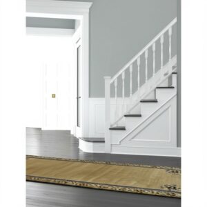 Gold runner rug featuring a dark decorative border lies on dark wood flooring near white stairs.