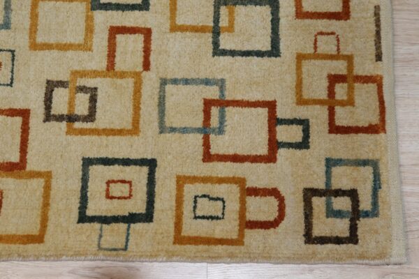 Geometric rug with cream background and repeating squares in burnt orange, mustard, teal, and brown.