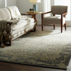 A dark gray rug featuring a distressed gold abstract pattern underlies a cream sofa and armchair.