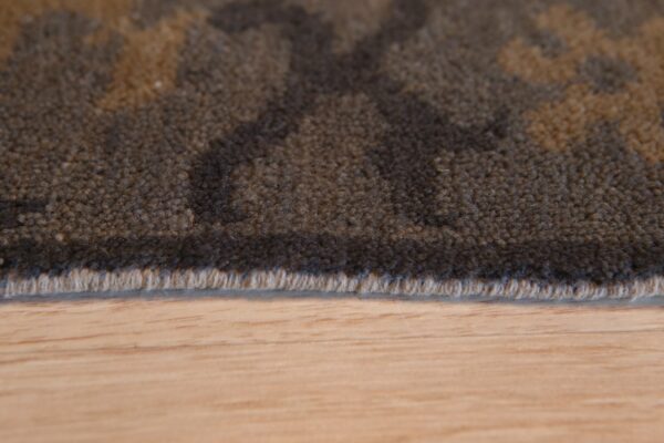 Dark brown textured rug with tan pattern detail rests on light wooden floor planks.