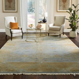 Blue and gold patterned rug defines a seating area with two cream wing chairs on dark wood floors.