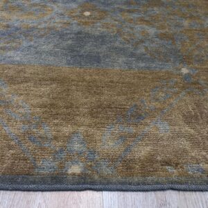 A high-pile rug with blue and brown distressed floral patterns rests on light plank flooring.