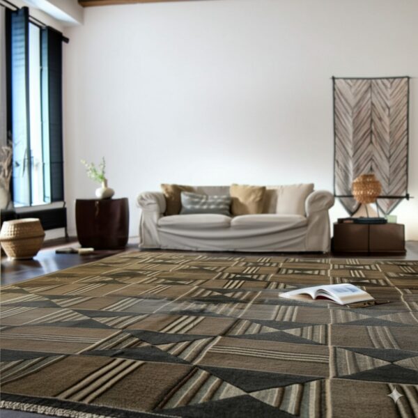 A large brown and gray geometric rug with striped blocks covers a dark floor in a sunny room.