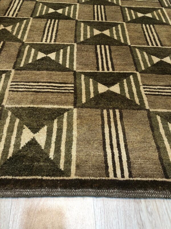 Textured brown and dark green geometric rug with stripes and hourglass patterns rests on light wood planks.