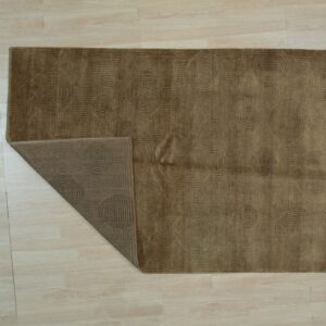 Brown geometric rug on light wood flooring, featuring concentric patterns with one corner turned back.
