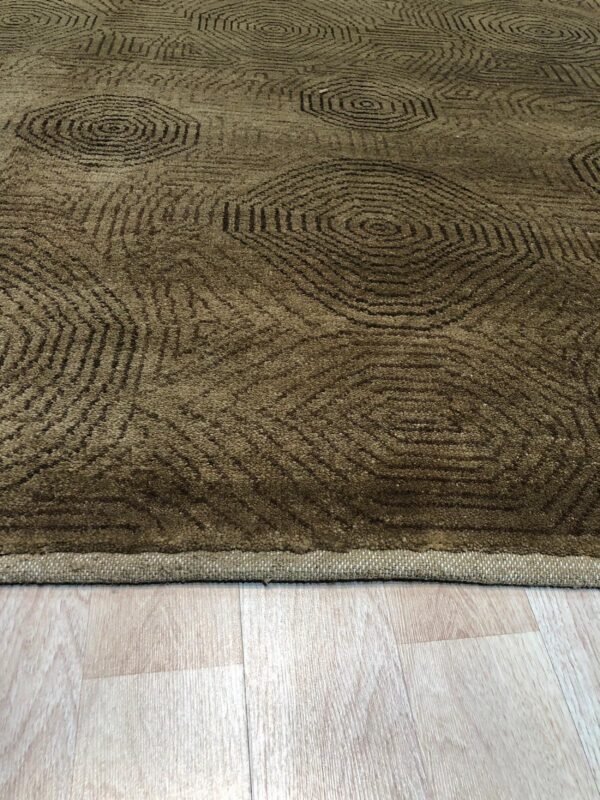 A textured olive rug with repeating dark geometric circles rests on pale blonde plank flooring.