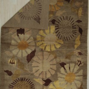 Brown and yellow floral rug folded back to show the reverse side on light wood plank flooring.