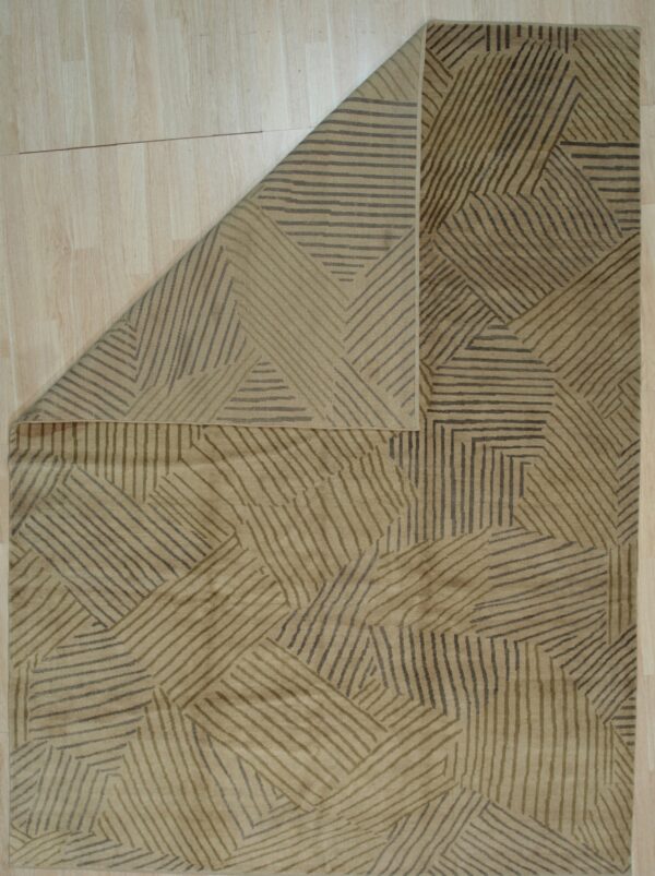 Taupe rug featuring an abstract pattern of dark and olive lines displayed on light plank flooring.