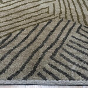 Close-up of a tan rug with an abstract linear pattern in olive green and dark gray over light wood flooring.