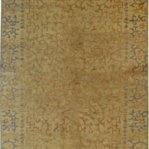 Gold rug with low pile, featuring abstract tone-on-tone motifs and a stylized border in slate gray and brown.