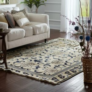 Cream rug with blue floral patterns sits on dark wood floors beside a white upholstered sofa.