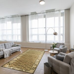 Olive geometric patterned runner rug on herringbone wood flooring surrounded by light gray tufted seating.