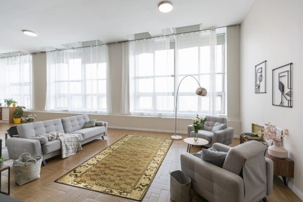 Olive geometric patterned runner rug on herringbone wood flooring surrounded by light gray tufted seating.