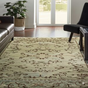 A scrolled sage green rug lies on dark hardwood, framed by a dark sofa and bright glass patio doors.
