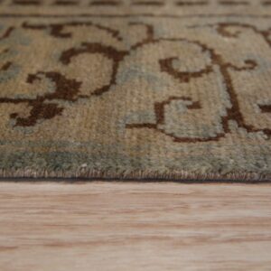 Close-up of a medium-pile tan rug featuring brown and sage patterns on light wood flooring.
