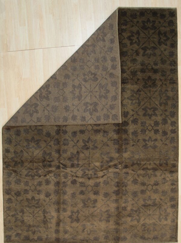 Dark brown rug with a tonal floral damask pattern displayed partially folded back on light wood flooring.