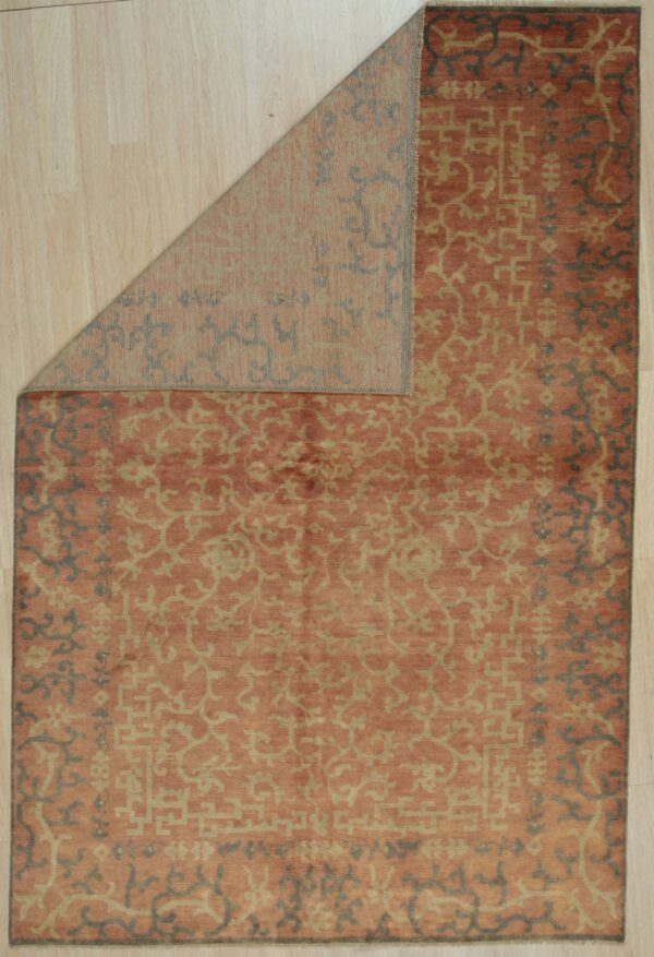 Orange and gold patterned rug displayed on light wood floor with a corner folded over.
