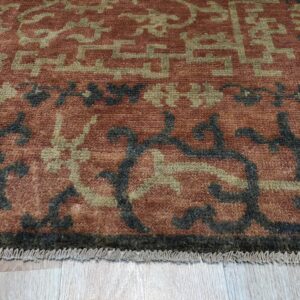 Close-up of a medium-pile rug featuring terracotta, sage, and dark gray patterns on light wood flooring.