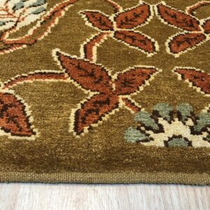 Brown botanical rug with rust, cream, and blue designs rests on light wood plank flooring.