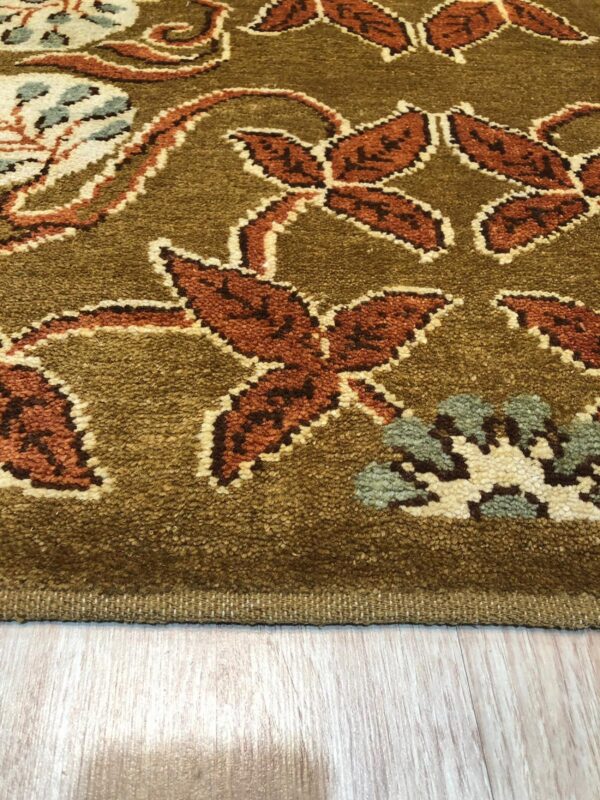 Brown botanical rug with rust, cream, and blue designs rests on light wood plank flooring.