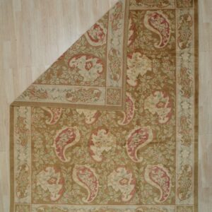 Classic khaki rug with cream and red floral paisley rests on light wood plank flooring, one corner folded back.