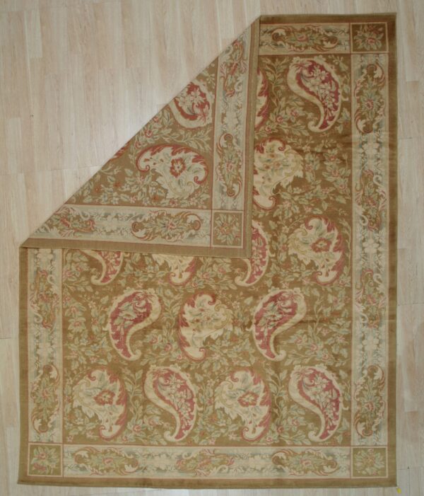 Classic khaki rug with cream and red floral paisley rests on light wood plank flooring, one corner folded back.