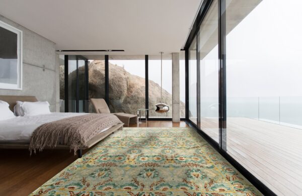 Blue, yellow, and rust patterned rug laid on dark wood flooring in a modern bedroom overlooking large rocks.