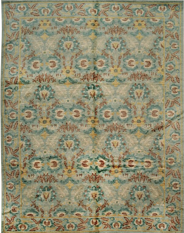 Teal and light blue area rug with a blurred traditional floral pattern in brown, cream, and gold.