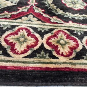 Textured rug detail in black, crimson, and cream highlights ornate floral and medallion borders on pale wood flooring.
