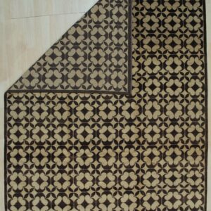 Brown and tan geometric rug on light wood floor with the top left corner folded over.
