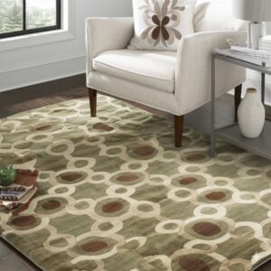 A green, brown, and beige interlocking circle rug sits beneath a neutral armchair and side table.