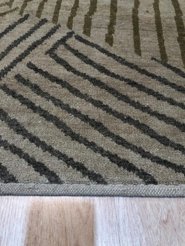 Textured beige rug featuring dark brown and khaki striped geometric patterns on wood planks.