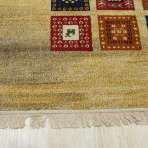 Textured, gold rug with multicolored geometric squares and fringe lies on pale wood flooring.