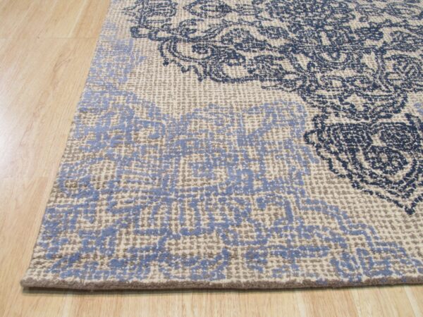 Highly textured rug with navy and light blue distressed patterns resting on light wood floor planks.