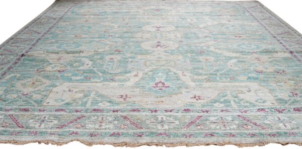 Faded traditional rug with low pile features teal, light gray, and magenta floral patterns.