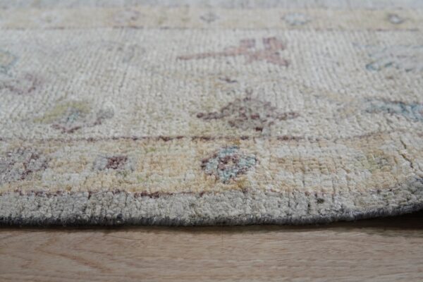 Thick, textured cream and beige rug with subtle multicolor patterns resting on light wood flooring.