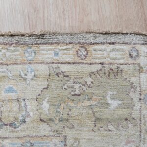 Muted high-pile rug detail showing abstract blue, cream, and mauve patterns on light wood flooring.