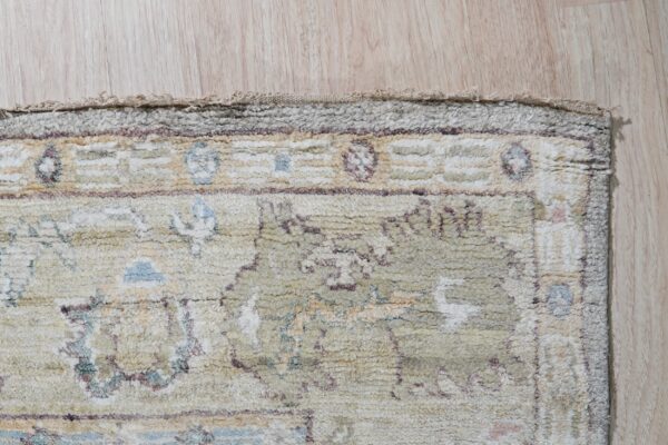 Muted high-pile rug detail showing abstract blue, cream, and mauve patterns on light wood flooring.