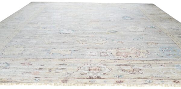 Pale gray low-pile rug featuring a distressed traditional floral pattern in muted blue, peach, and tan.