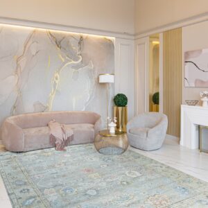 Distressed blue traditional rug on white marble floor beneath a pink velvet sofa and gold accents.
