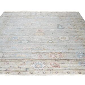 Light gray area rug featuring a distressed floral medallion pattern in pale blue, dusty pink, and yellow.