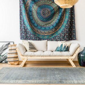 Low-pile blue and gray distressed patterned rug under a natural wood sofa on wood floors.