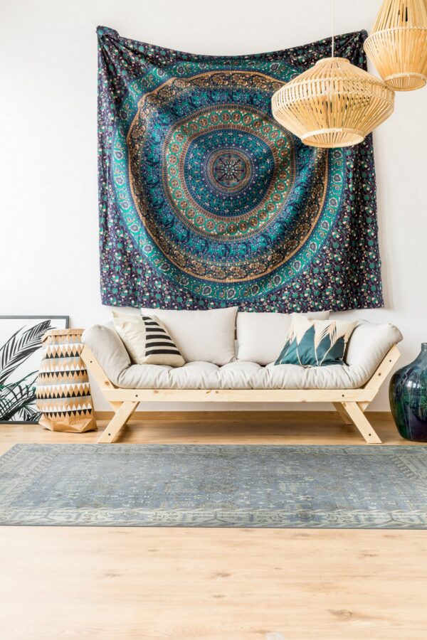Low-pile blue and gray distressed patterned rug under a natural wood sofa on wood floors.