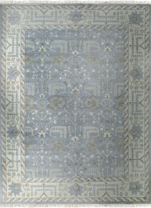 Low-pile rug in light blue and cream with traditional geometric floral motifs and short fringe.